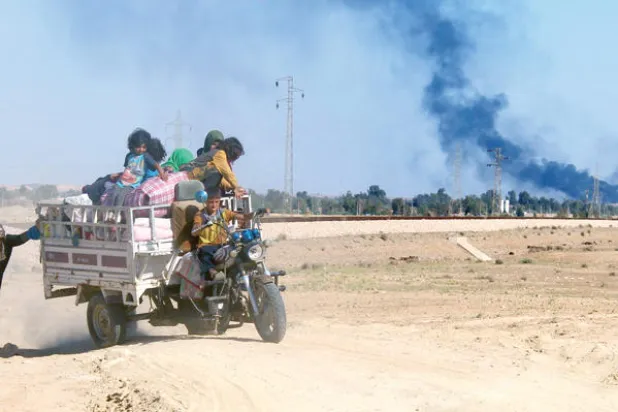 عراقية تدفع بعجلة بعد إعلان الحكومة إخلاء مئات من العراقيين من مدينة هيت في محافظة الأنبار للوصول إلى أماكن آمنة في محاولة لدخول المدينة وطرد {داعش} منها (أ.ف.ب)