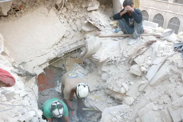 عناصر من قوات الدفاع المدني يبحثون عن ضحايا القصف الجوي على حي بستان الباشا الذي يخضع لسيطرة المعارضة (أ.ف.ب)