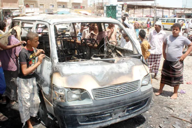 يمنيون يتجمعون قرب سيارة تعرضت لعمل إرهابي في مدينة لحج (أ.ف.ب)