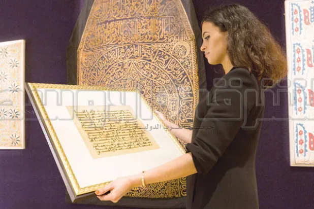 عارضة في مزاد بونهامز تتطلع إلى مخطوطة بالخط الكوفي داخل صالة الفنون الإسلامية أمس (تصوير: جيمس حنا)