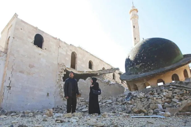 رجل وزوجته قرب مسجد مدمر في حلب (غيتي)