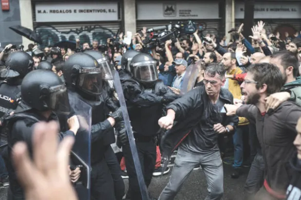 اشتباكات بين ناخبين وقوات مكافحة الشغب الإسبانية في برشلونة أمس (أ.ف.ب)