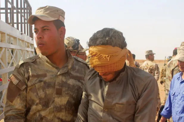 جندي عراقي يعتقل عنصراً محتملاً من {داعش} (أ.ف.ب)