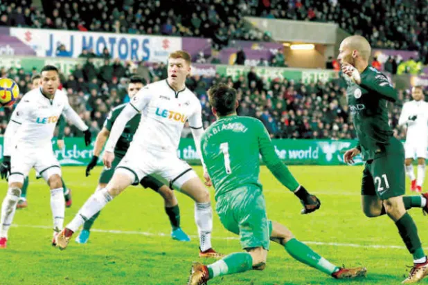 سيلفا نجم مانشستر سيتي (يمين) يسجل في مرمى سوانزي رغم الحصار الدفاعي (رويترز)