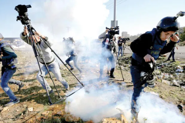 الإعلام في قلب الحدث. صحافيون يغطون «يوم الغضب» برام الله في 8 ديسمبر احتجاجاً على إعلان ترمب والغاز المسيل للدموع يعطل عملهم (رويترز)
