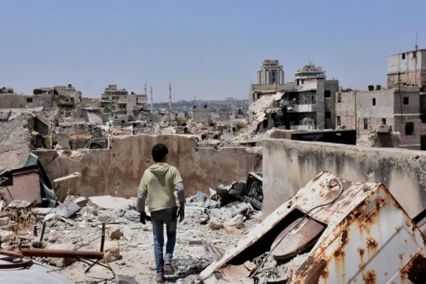 طفل سوري يسير وسط أنقاض المباني المدمرة في مدينة حلب (أ.ف.ب)