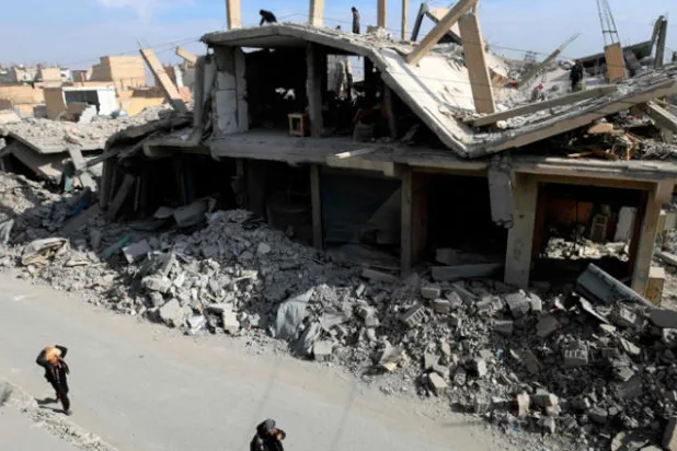 سوريون يحملون خبزاً في طريق عودتهم إلى منازلهم في مدينة الرقة التي طردت قوات يهيمن عليها الأكراد تنظيم داعش منها العام الماضي (أ.ف.ب)