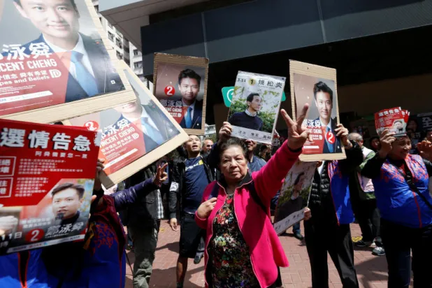 مؤيدون للمرشح المؤيد للحكومة فينسنت تشينغ يحاولون منع أحد مؤيدي المرشح المؤيد للديمقراطية إدوارد ييو خلال انتخابات فرعية للمجلس التشريعي في هونغ كونغ (رويترز)