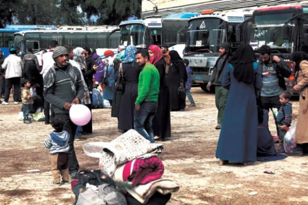 مدنيون ومقاتلون معارضون في قلعة المضيق قبل انتقالهم إلى إدلب أول من أمس (أ.ف.ب)