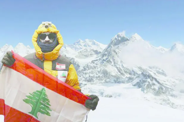 المغامر نضال صلح يحمل العلم اللبناني وخلفه قمة إفرست أعلى قمة في العالم 