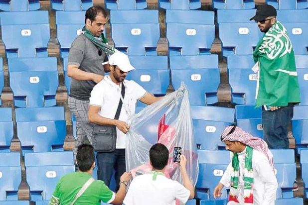 جماهير سعودية تساعد في تنظيف المدرجات بعد نهاية المباراة (أ.ف.ب)