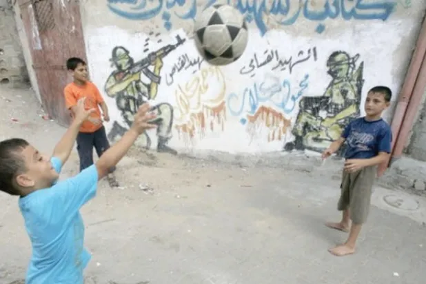 أطفال فلسطينيون يلعبون الكرة في أحد المخيمات