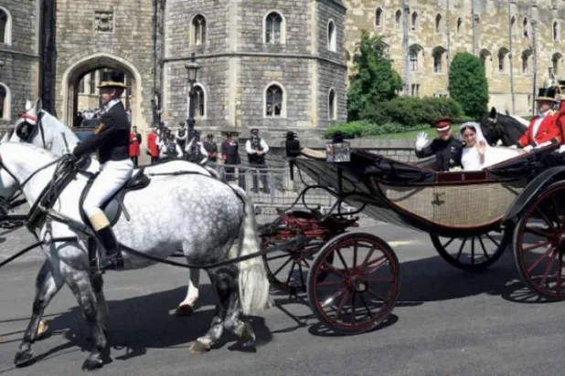 Prens Harry ve eşi Megan, düğün törenleri esnasında Windsor Kalesi dışındaki vatandaşları selamlarken (AFP)