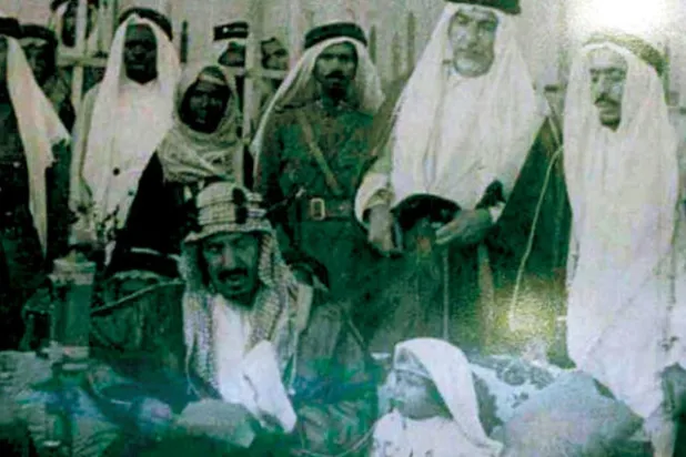 المؤسس الملك عبد العزيز بن عبد الرحمن آل سعود يلقي خطاباً سياسياً وعلى يساره خادم الحرمين الشريفين الملك سلمان حينما كان طفلاً في صورة التقطت عام 1938 («الشرق الأوسط»)