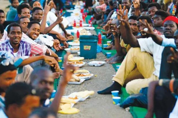 Sudanlı protestocular Hartum'daki Savunma Bakanlığı karargahının önünde iftar yaptıkları sırada (AFP)