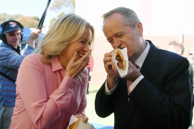 زعيم المعارضة الأسترالية بيل شورتن وزوجته كلوي يأكلان نقانق الديمقراطية بعد الإدلاء بصوتيهما في ملبورن (إ.ب.أ)