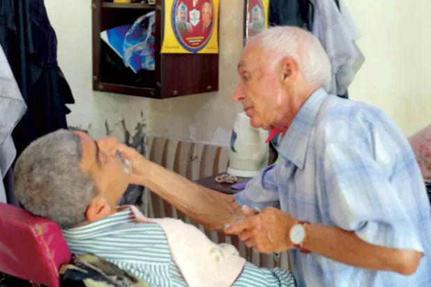 العم زكي يحلق ذقن أحد زبائنه