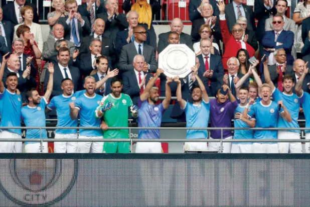 لاعبو مانشستر سيتي على منصة التتويج يحتفلون بالدرع الإنجليزية الخيرية (رويترز)