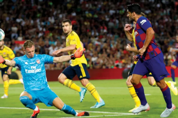 سواريز نجم برشلونة (يمين) يسدد نحو مرمى آرسنال في مباراة كأس غامبر الودية (رويترز)