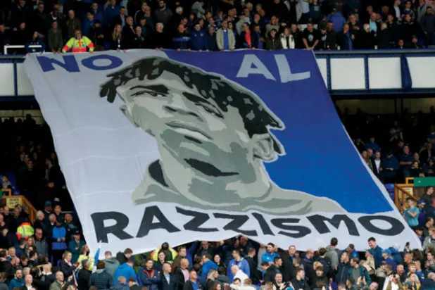 مشجعو إيفرتون يرفعون لافتة تحمل وجه مويس كين وشعاراً باللغة الإيطالية معناه «لا للعنصرية»