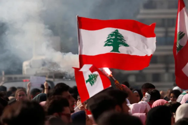 متظاهرون يحملون الأعلام اللبنانية في العاصمة بيروت (رويترز)