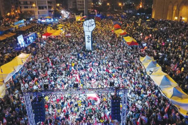 کل بیروت کے شہداء اسکوائر میں دسیوں ہزار لبنانی مظاہرین کو لبنانی پرچم اٹھا کر انقلاب کا نعرہ بلند کرتے ہوئے دیکھا جا سکتا ہے (اے ایف پی)