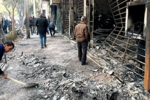ایران کے مرکزی شہر اصفہان میں مظاہروں کے دوران جلے ہوئے ایک بینک کے سامنے اہل ایران کو دیکھا جا سکتا ہے