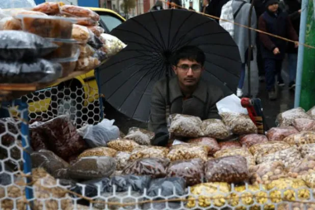 ایرانی دار الحکومت میں گذشتہ روز ایک بیچنے والے کو بارش سے پناہ لیتے ہوئے دیکھا جا سکتا ہے