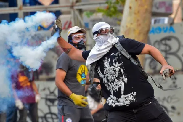 متظاهر يرمي قنبلة مسيلة للدموع باتجاه القوات الأمنية (أ.ف.ب)