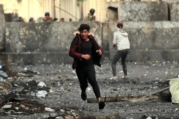 متظاهر يرمي الحجارة بينما تحاول القوات الأمنية إغلاق أحد الشوارع في بغداد (أ.ب)
