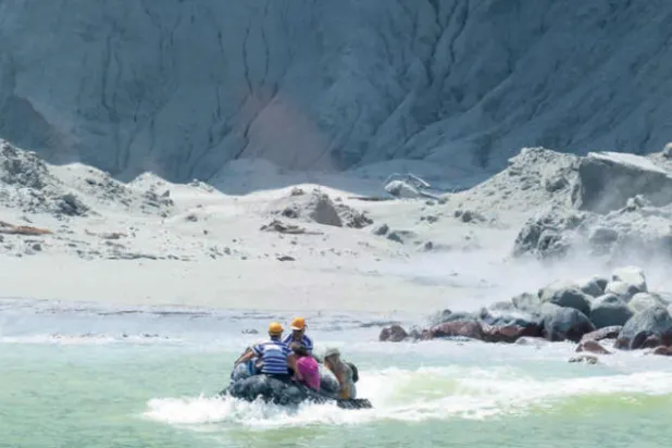 سياح على متن قارب يفرون من انفجار بركان في نيوزيلندا (إ.ب.أ)