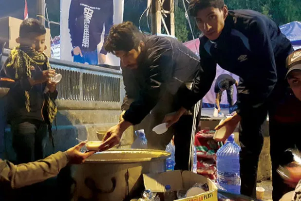 شاب يوزع حساء العدس (الشوربة) مجاناً (الشرق الأوسط)