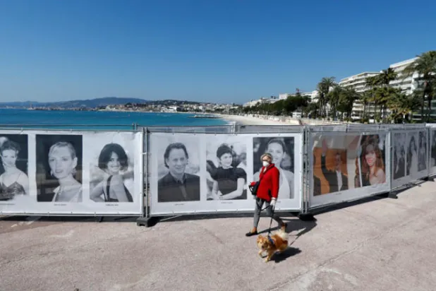 امرأة تمشي أمام صور سابقة للمهرجان السينمائي في كان أمس (رويترز)