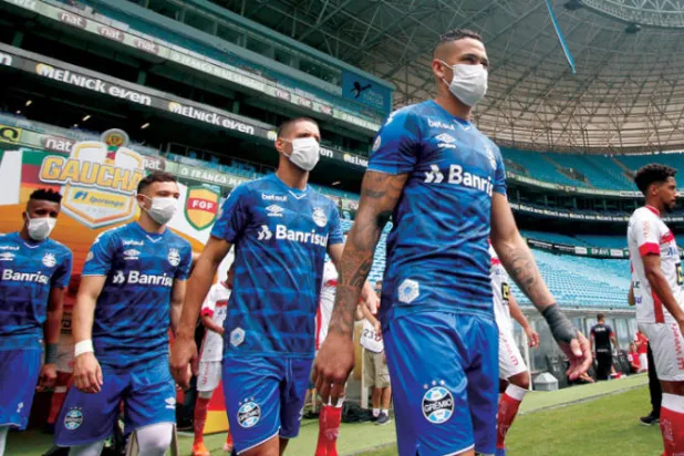 لاعبو فريق غريميو بالأقنعة اعتراضاً على اضطرارهم للعب أمام ساو لويز (أ.ف.ب)