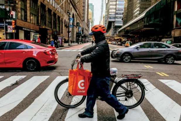 لي مينغبا يعمل لدى تطبيق «كافيار» لتوصيل الطعام