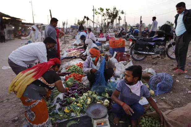 يشترون خضاراً في مدينة الله أباد الهندية (أ.ب)