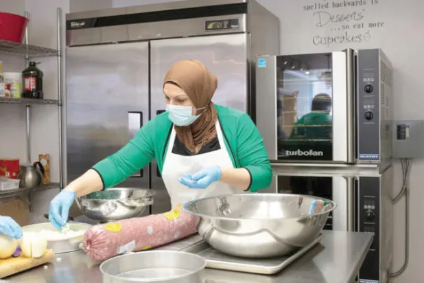 نداء عباس تطهو طعاماً لحساب منظمة تعين اللاجئين الطهاة (نيويورك تايمز)