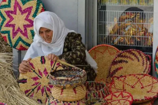 أم يوسف تتفقد قطعاً صنعتها من القش