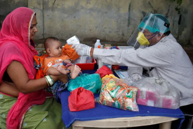 طبيب هندي يستخدم الأشعة تحت الحمراء لقياس درجة حرارة طفل (رويترز)