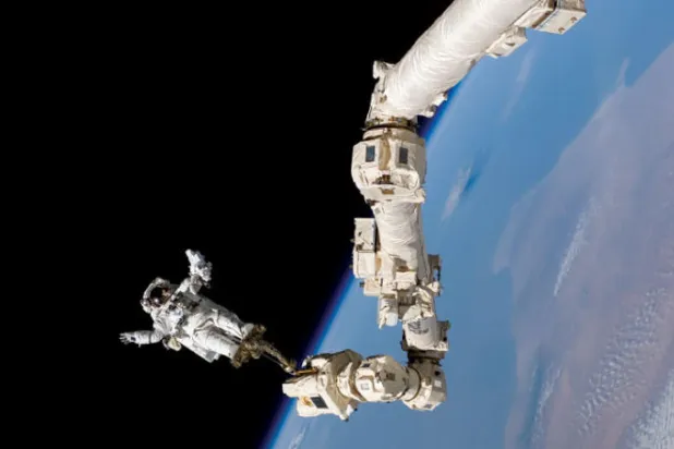 رائد الفضاء الأميركي ستيفن روبنسون يرتكز على ذراع «كندآرم 2» الروبوتية في المحطة الفضائية الدولية عام 2005