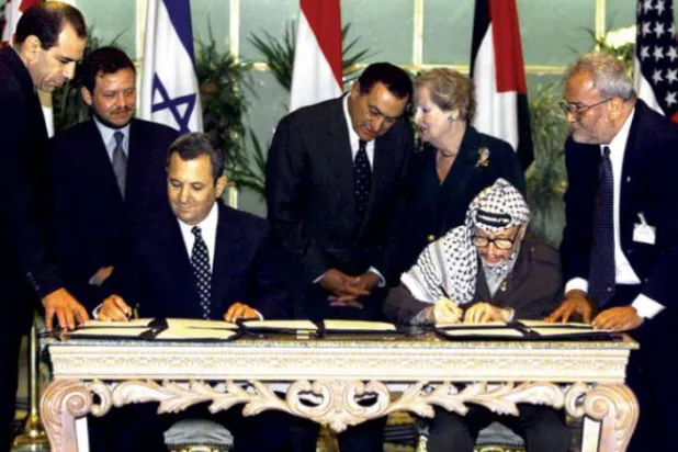 Ureykat (sağda), Filistin lideri Yaser Arafat ile 1999'da Ehud Barak ile bir anlaşma imzalarken, son Filistin lideri Yaser Arafat ile.
