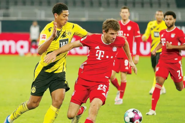 بيلينغهام بقميص دورتموند (يسار) في صراع على الكرة مع مولر مهاجم بايرن ميونيخ (رويترز)