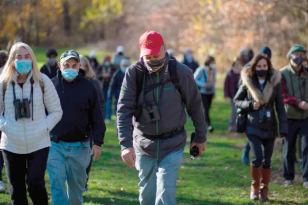 روبرت ديكانديدو مرتدياً قبعته الحمراء الشهيرة يقود مجموعة من مراقبي الطيور في «سنترال بارك» (أ.ف.ب)