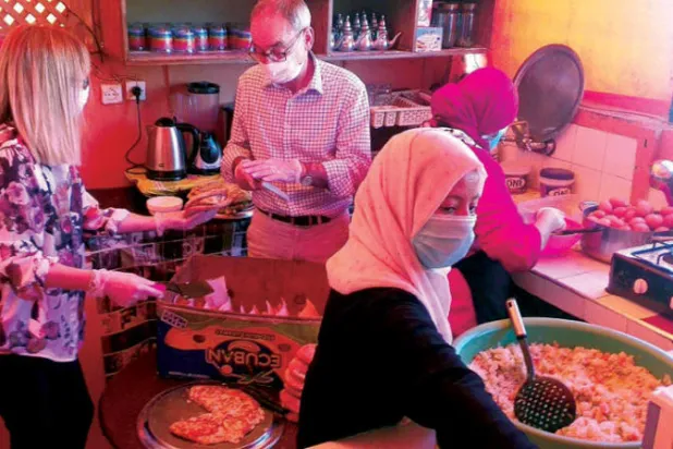 السفير البريطاني يساهم وزوجته في إعداد الوجبات وتجهيزها قبل توزيعها على المحتاجين