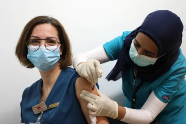 عاملة صحة تتلقى لقاح «كورونا» في المركز الطبي للجامعة الأميركية ببيروت (رويترز)