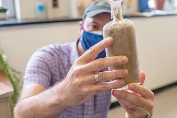 أحد العلماء يعرض الزجاجة التي خزنت فيها البذور (نيويورك تايمز - جامعة ميشيغان)