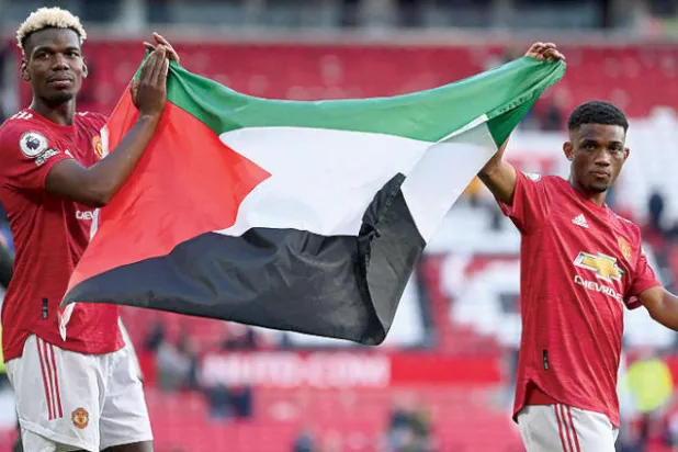 بوغبا وديالو يطوفان حول ملعب «أولد ترافورد» بعلم فلسطين بعد مباراة يونايتد وفولهام (أ.ف.ب)