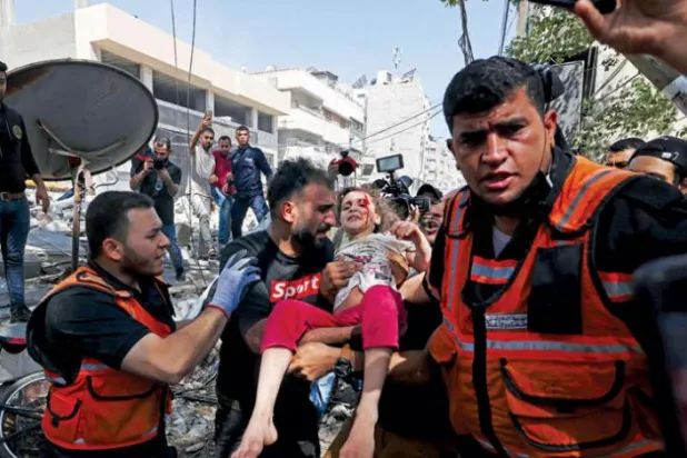 گزشتہ روز غزہ میں اسرائیلی حملہ کے نتیجے میں تباہ شدہ عمارت کے ملبے کے درمیان تلاشی اور بچاؤ کی کارروائی کے ساتھ ساتھ راحت کاروں کے ذریعہ ایک بچے کو ملبے کے نیچے سے نکالے جانے کے منظر کو دیکھا جا سکتا ہے (اے ایف پی)