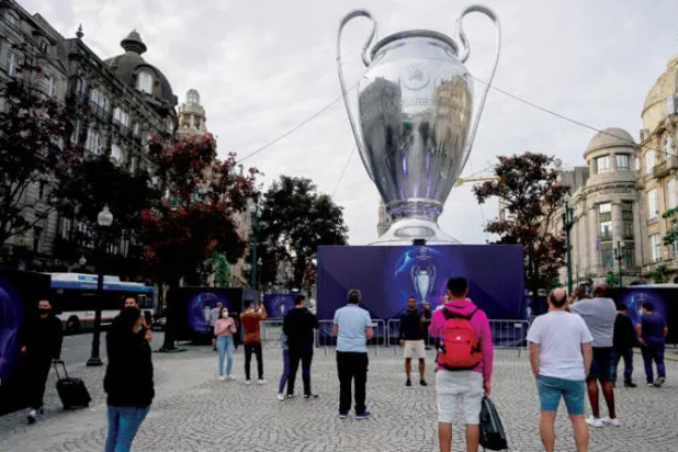 مشجعون بجانب نموذج ضخم لكأس دوري أبطال أوروبا في بورتو (أ.ب)