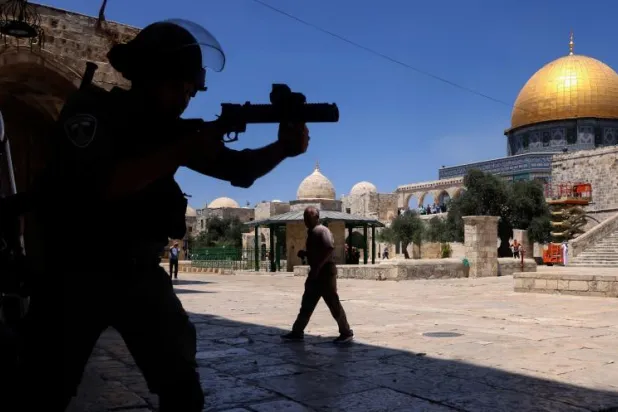 شرطي إسرائيلي يطلق الرصاص المطاطي في اتجاه فلسطينيين داخل حرم المسجد الأقصى (أ.ف.ب)